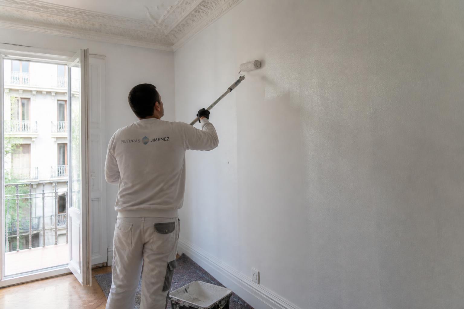 Aplicación de pintura blanca con rodillo en pared interior